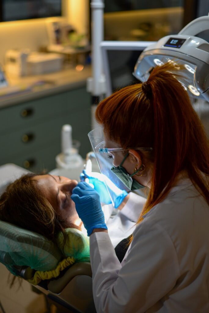 Dentista esegue un restauro conservativo dentale con lampada polimerizzante su una paziente