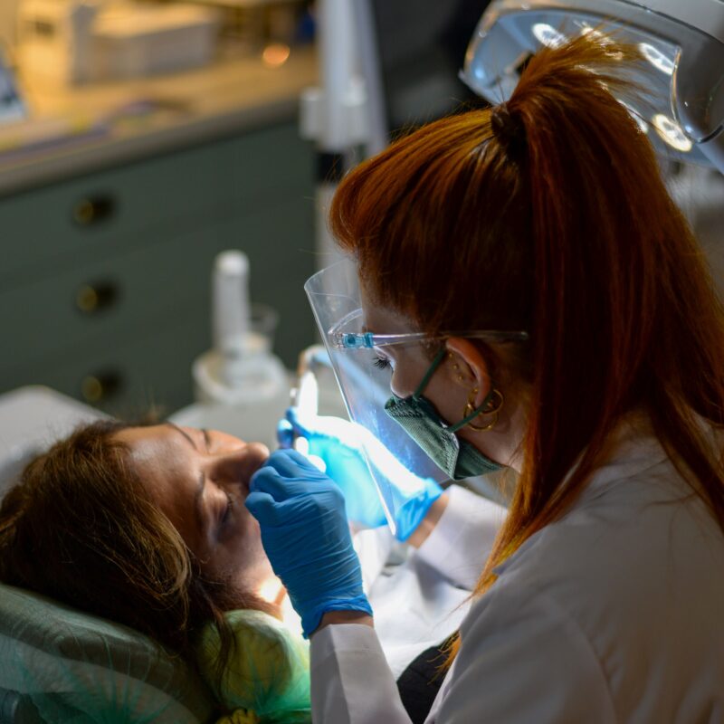 Dentista esegue un restauro conservativo dentale con lampada polimerizzante su una paziente