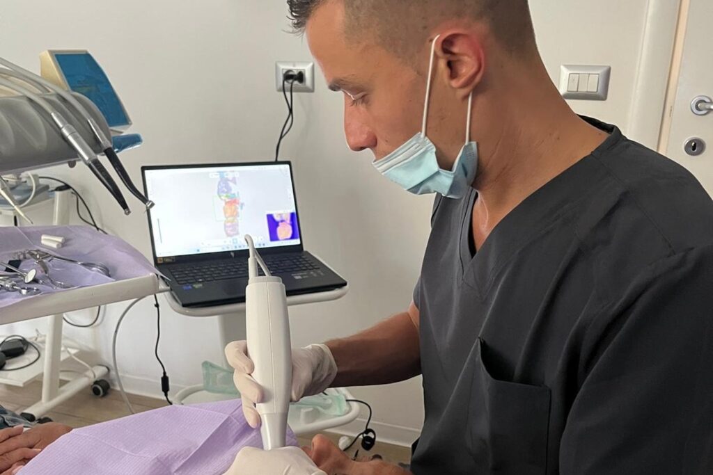 Il dott. Gianmarco Muzzi esegue un’impronta dentale digitale con lo scanner intraorale; sul portatile la scansione 3D dell’arcata