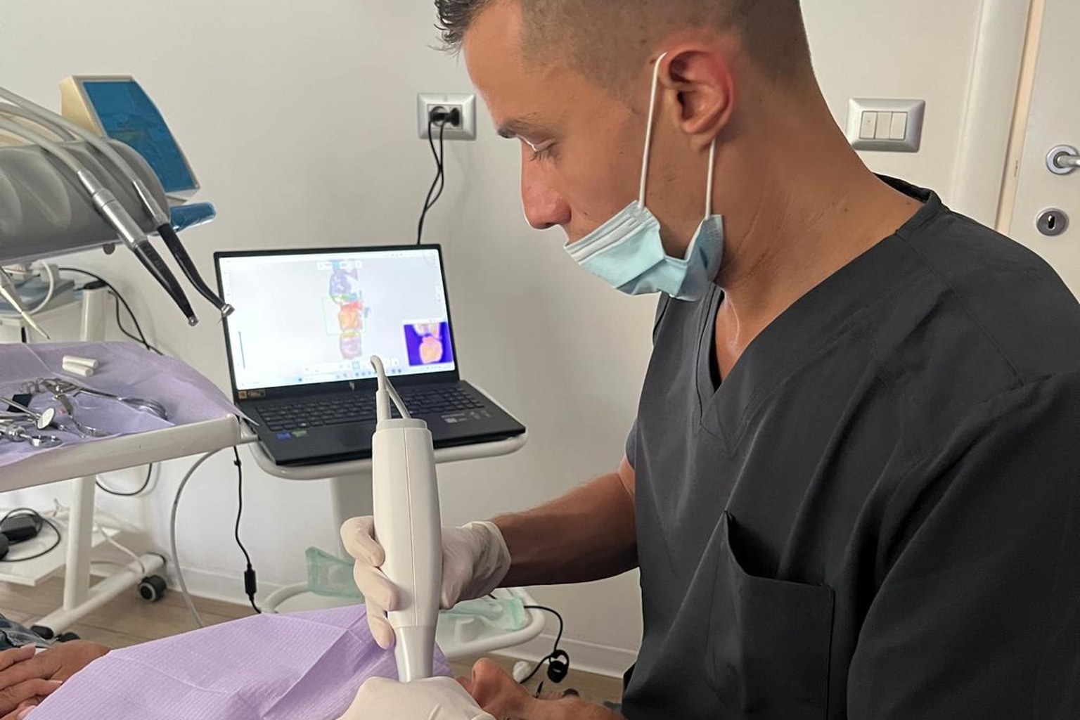 Il dott. Gianmarco Muzzi esegue un’impronta dentale digitale con lo scanner intraorale; sul portatile la scansione 3D dell’arcata