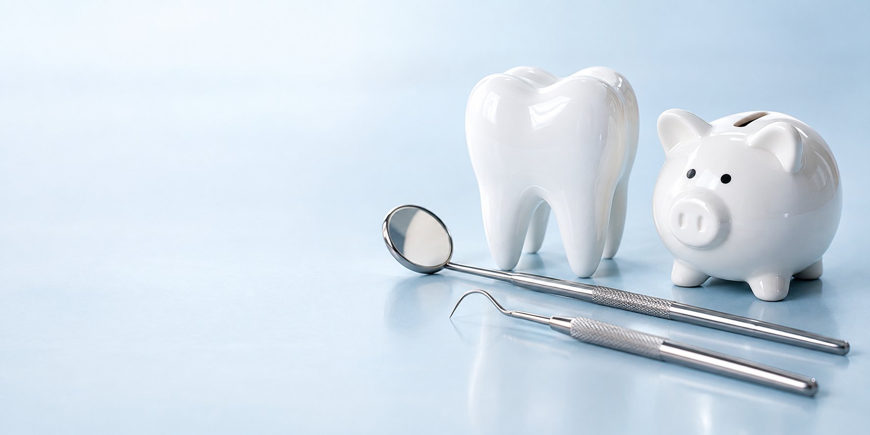 Modello di dente, specchietto e sonda dentale accanto a un salvadanaio: la prevenzione dentale è anche risparmio